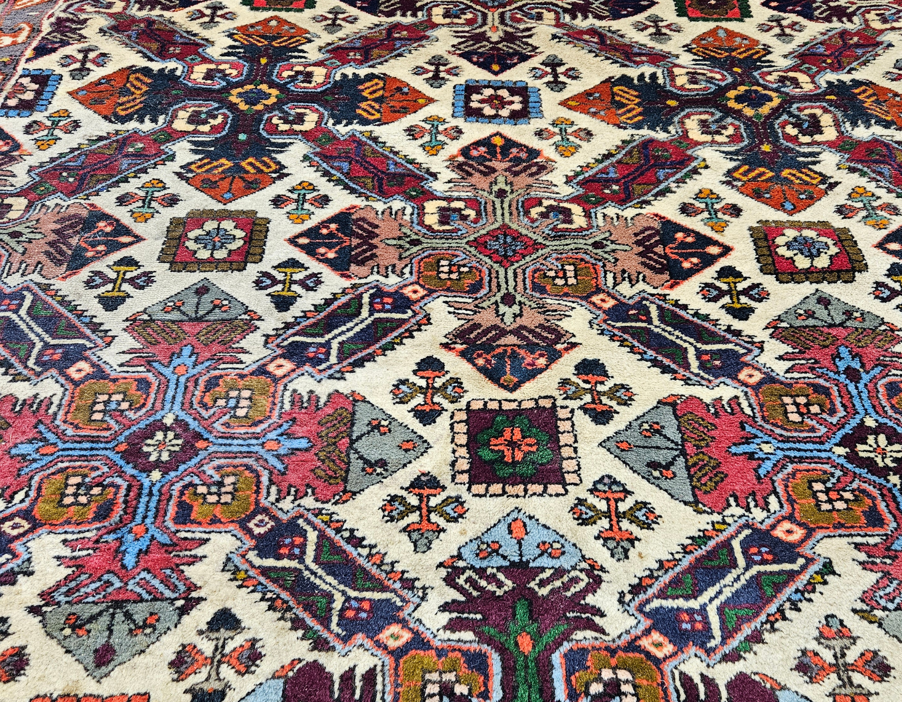Detailed antique rug pattern in vivid blue, terra cotta, and plum tones